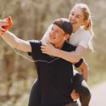 Pareja joven sacándose una selfie alegre en plena naturaleza para inmortalizar un momento especial con su smartphone.